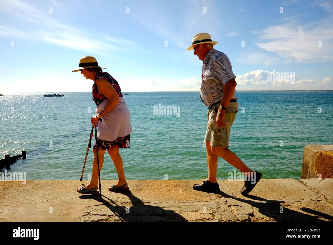 Elderly couple going for a walk along the seafront revetment promenade Totland Bay Isle of Wight Stock Photo
