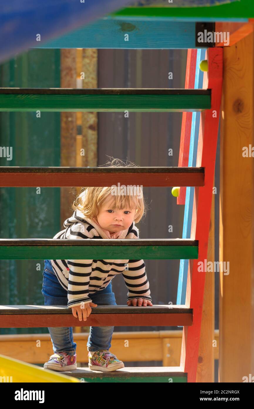 cute little toddler girl climbing stairs of a children's slide Stock Photo