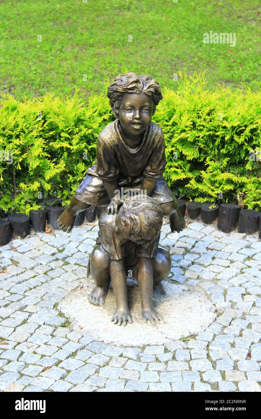 Bronze sculpture of children playing leapfrog in summer park Stock Photo