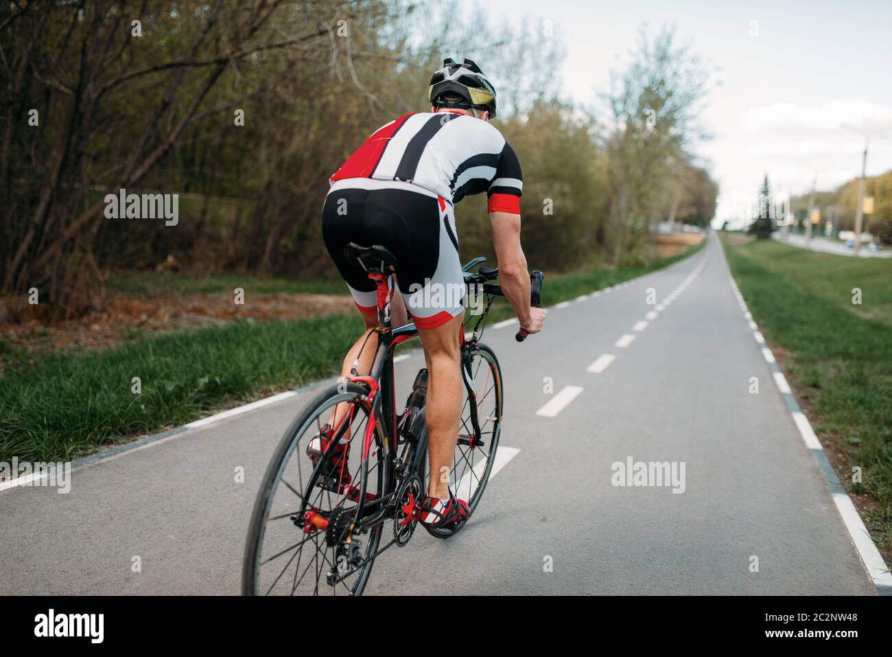 Cyclist in helmet and sportswear rides on bicycle, back view. Workout ...