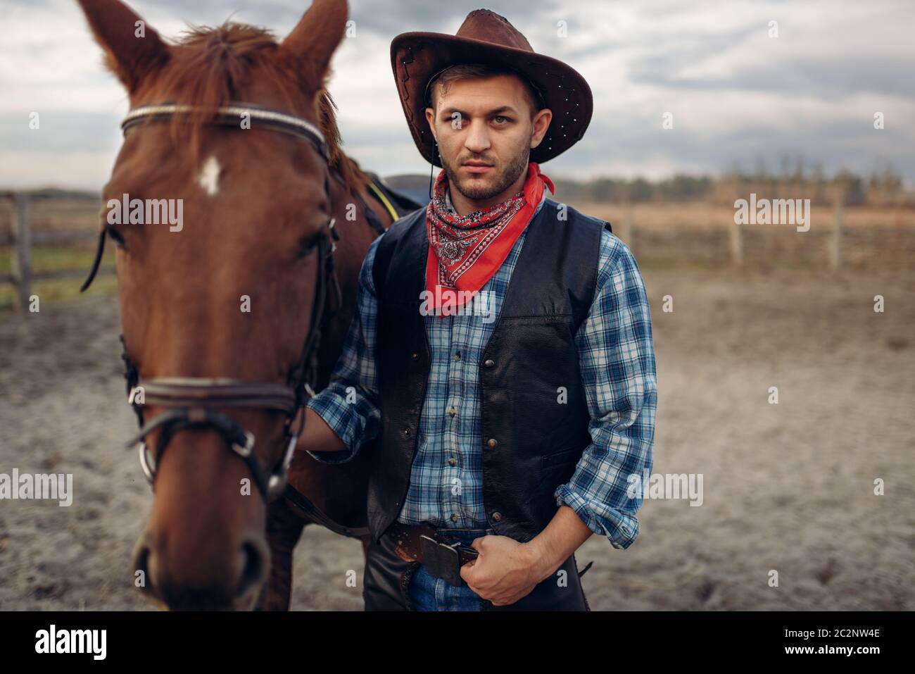 Cowboy in jeans and leather jacket poses with horse on texas farm ...