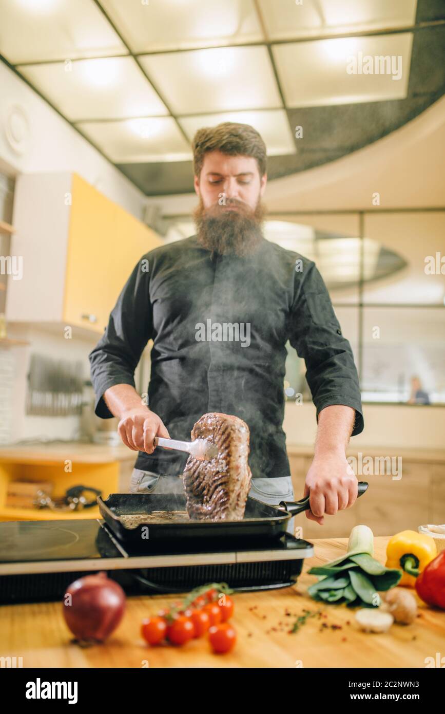 Male person cooking meat in a pan on the kitchen. Man preparing boiled ...