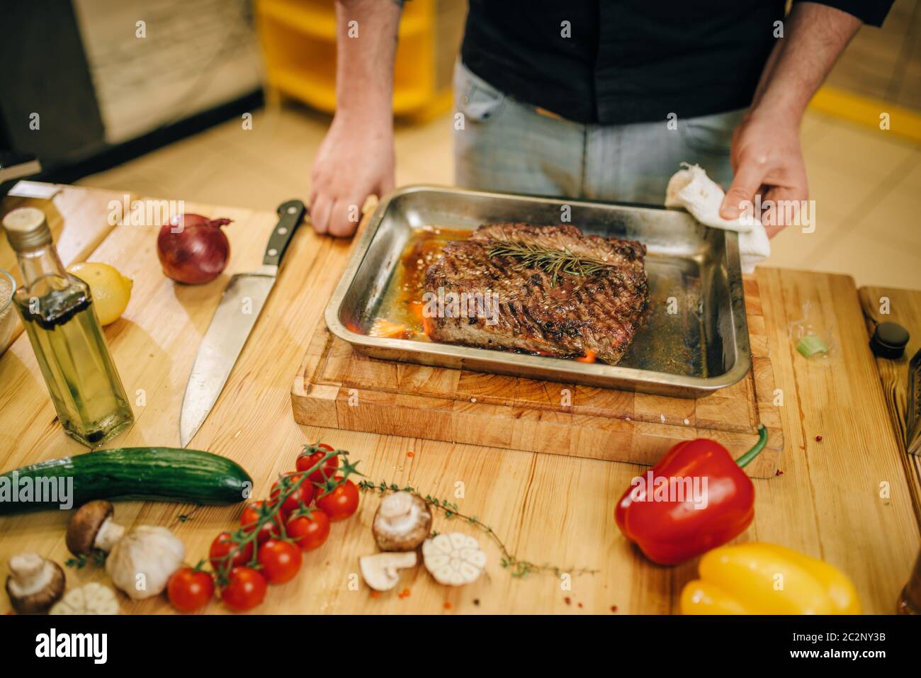 Male chef at the pan with roasted meat and vetables, kitchen on ...
