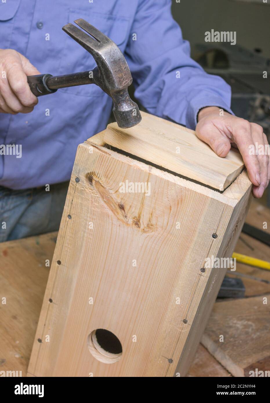 Carpenter inserts the bottom of the birdhouse Stock Photo
