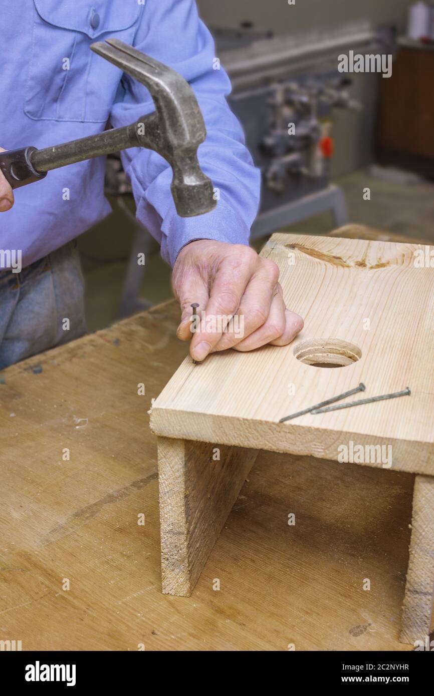 Carpenter knocks together parts of the birdhouse Stock Photo
