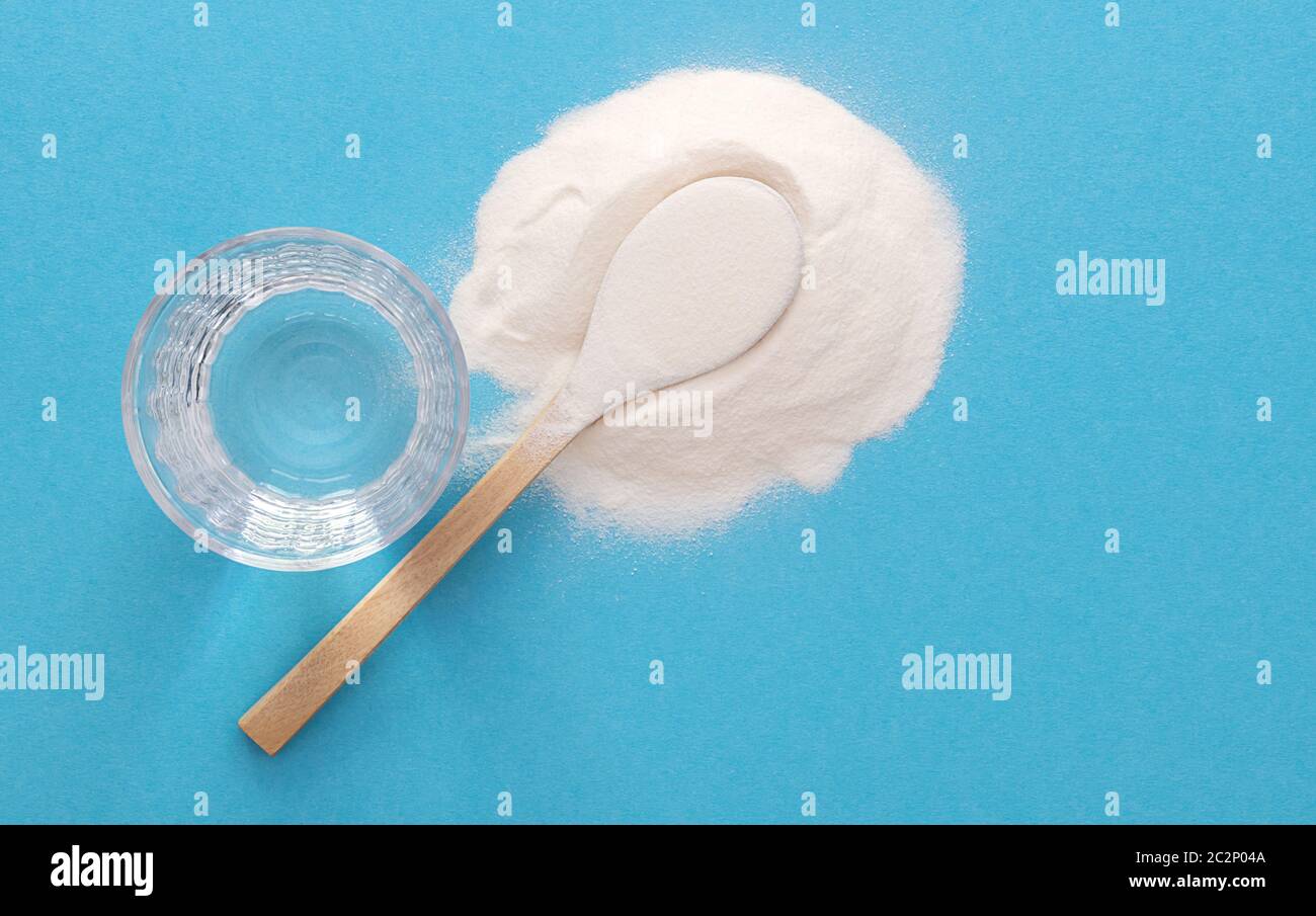 Collagen peptides powder and water on blue surface. Healthy skin and joint concept. Stock Photo
