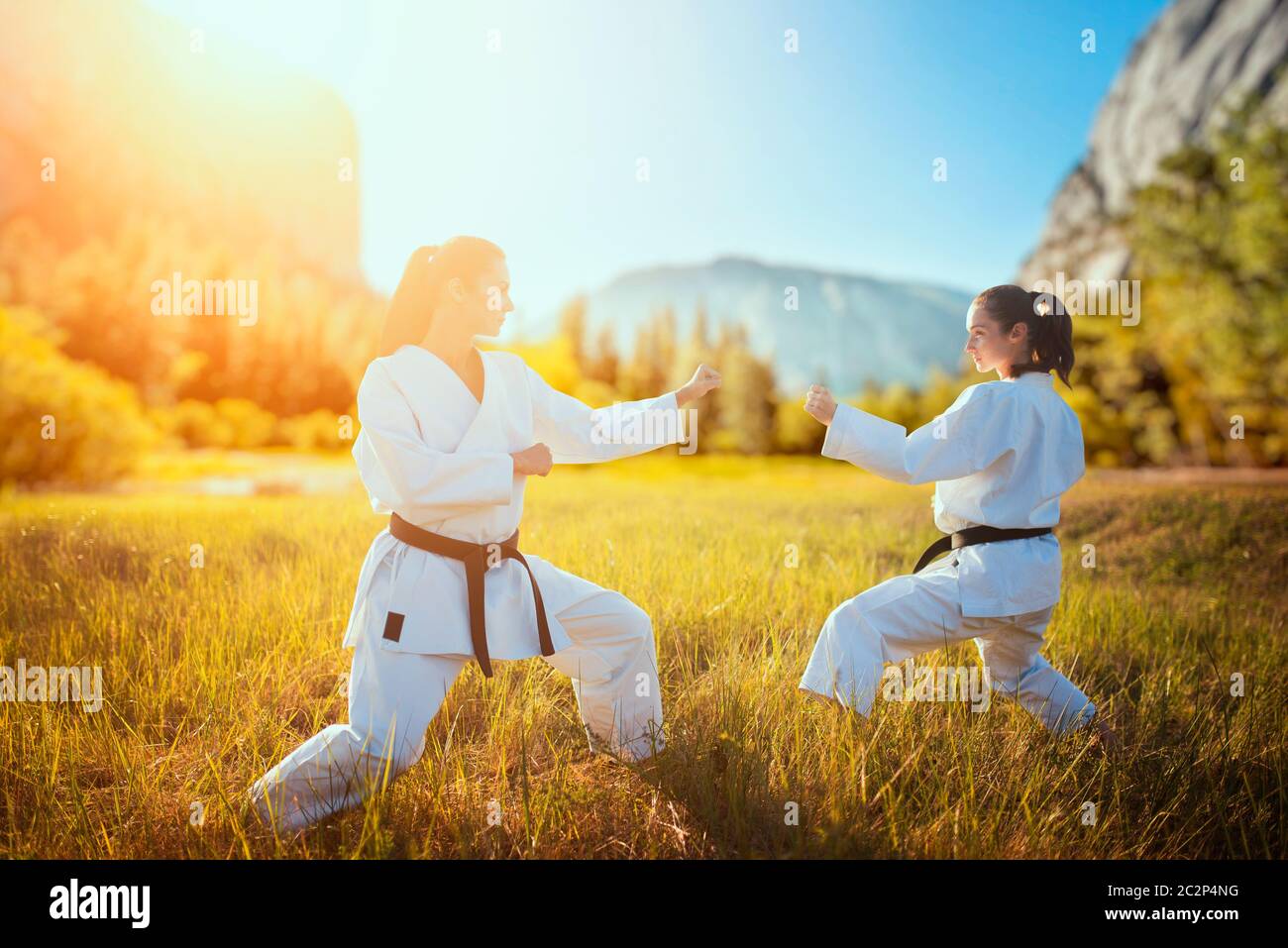 Two female karate in kimono training combat skill in summer field