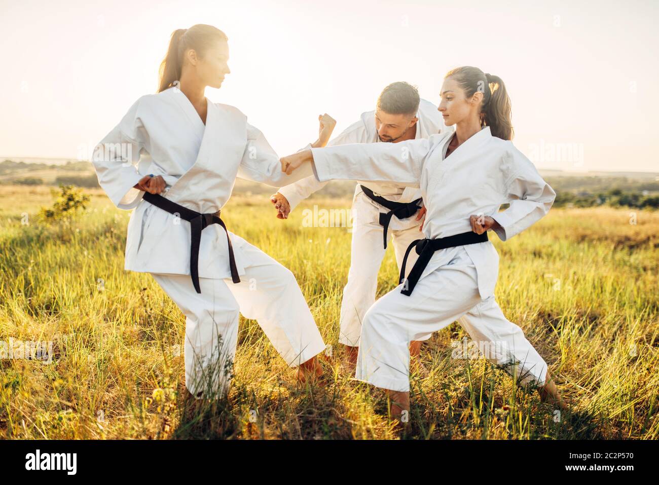 Two female karate fighters in white uniform with black belts on