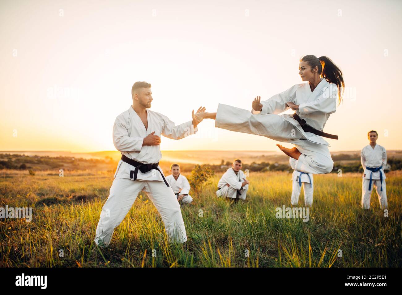 Female karate fighter trains kick in flight with master. Martial art