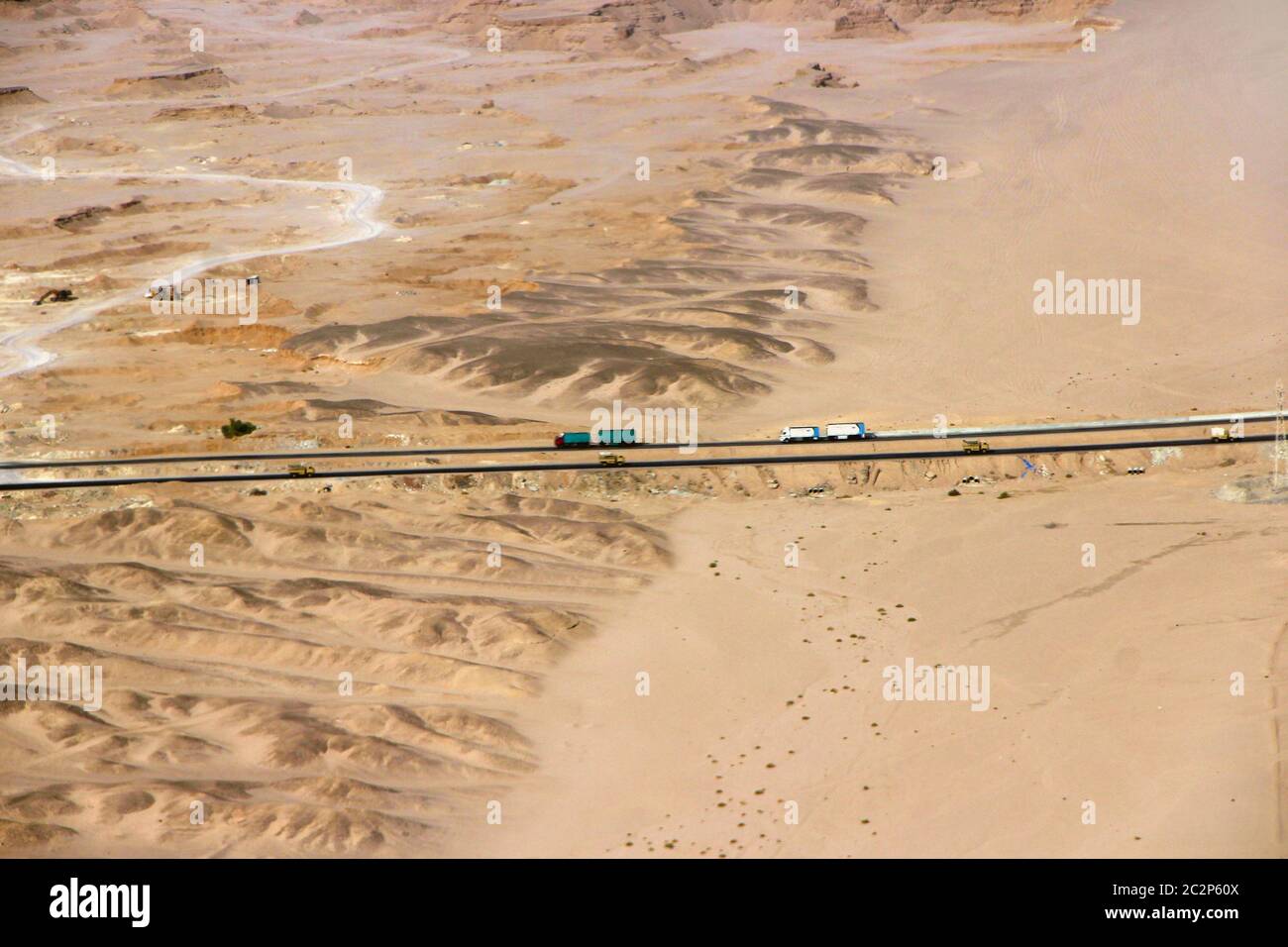 Beautiful view onto asphalt road in wild sandy lands of desert. Aerial scenery view of highway passi Stock Photo