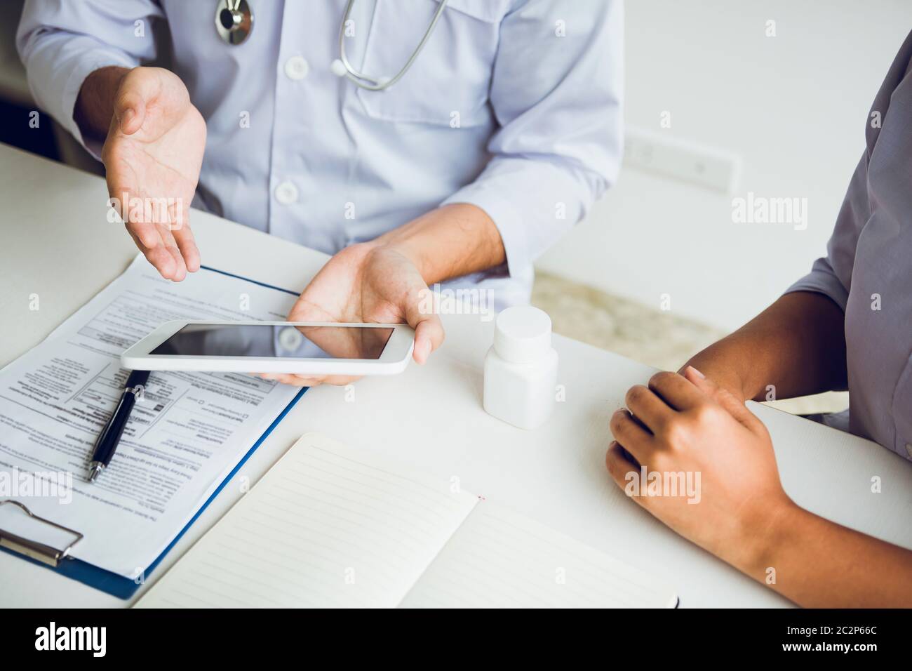 Asian doctor talking the patient at clinic while using the tablet ...