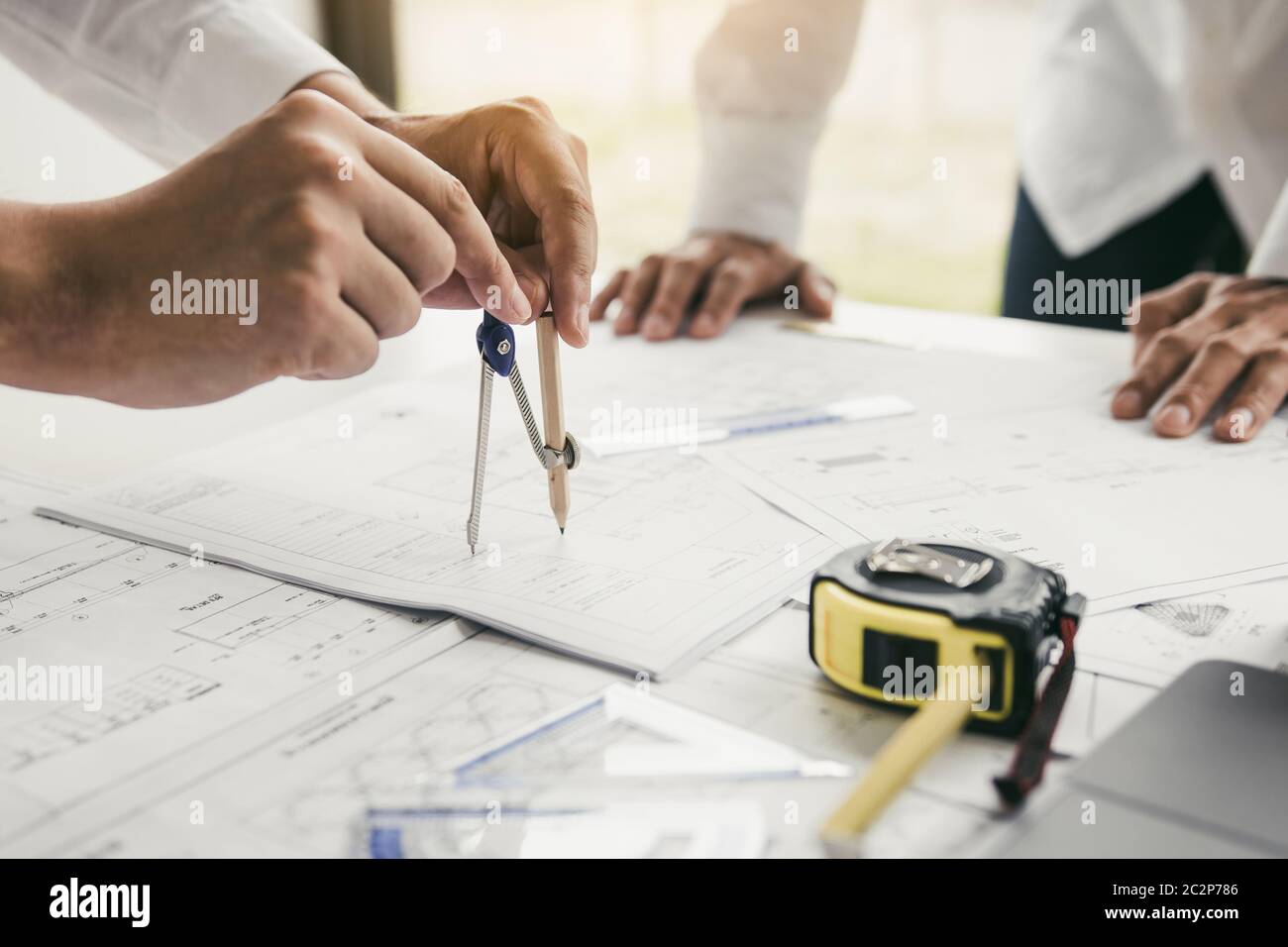 Two engineering working together and using compass looking blueprint ...