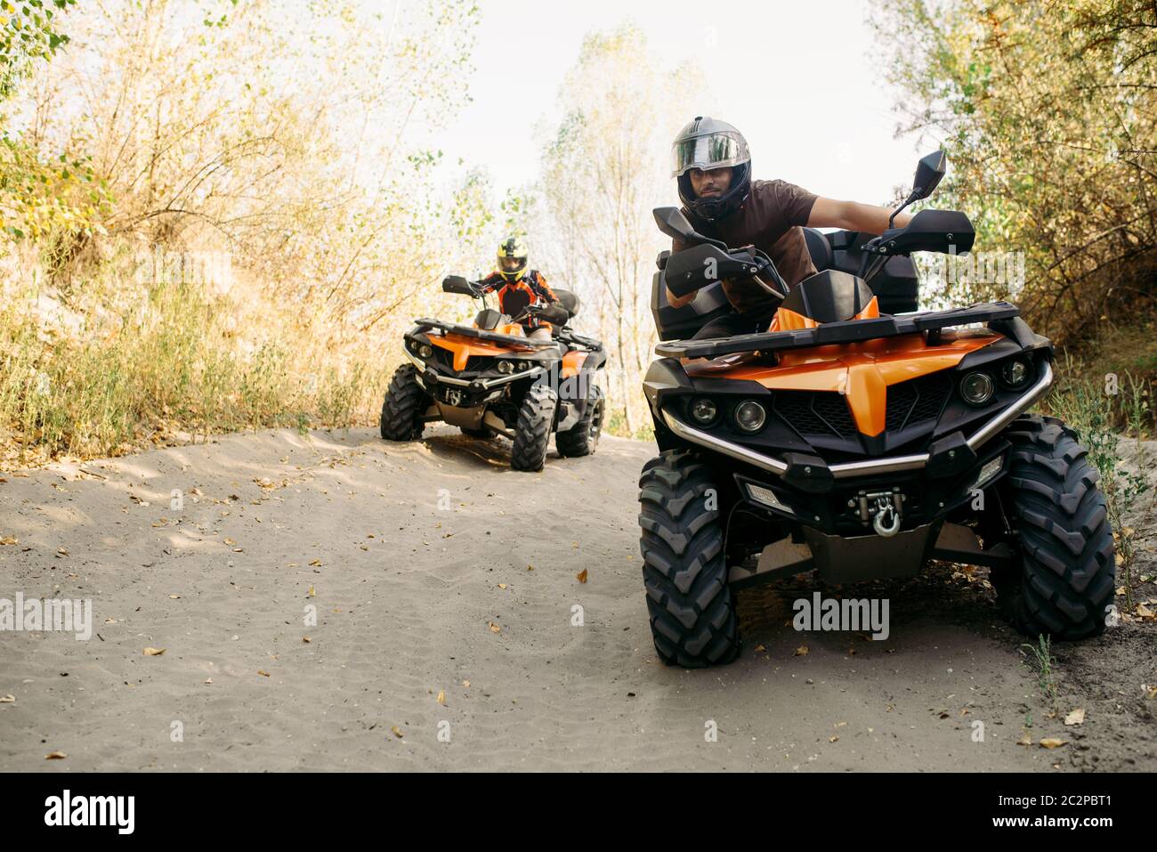 Two quad bike riders in helmets travels in forest, front view. Riding on atv,  extreme sport and travelling, quadbike adventure Stock Photo - Alamy