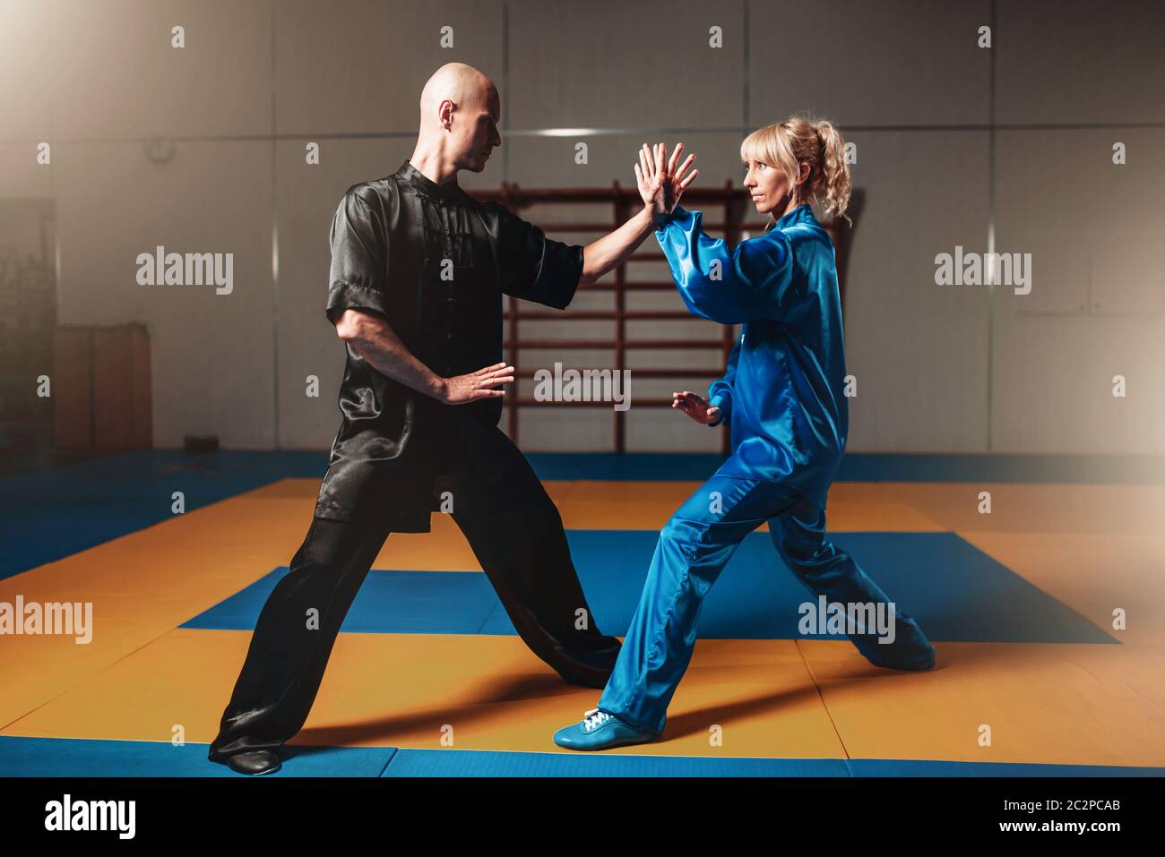 Male and female wushu fighters exercises indoor, martial arts. Sparring