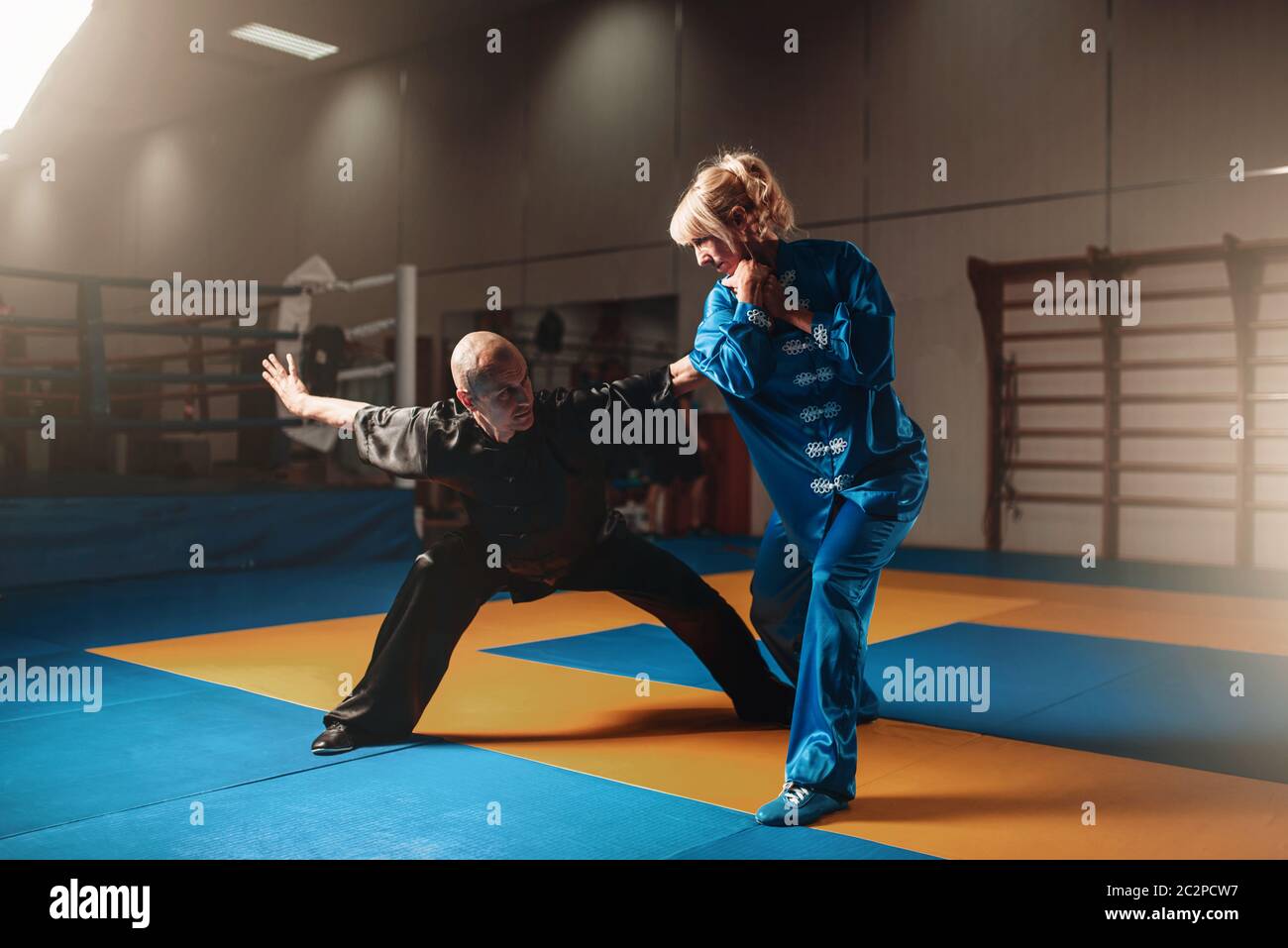 Male and female wushu fighters exercises indoor, martial arts. Sparring