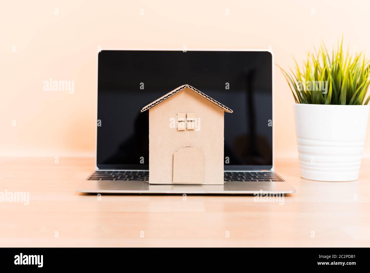 Cardboard paper model house and computer laptop, property mortgage rent buy concept Stock Photo