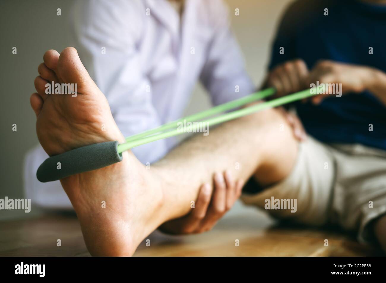 Patient use resistance band stretching out his leg with physical