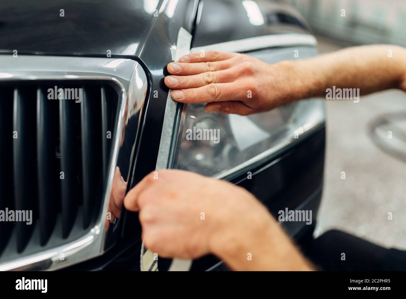Auto detailing of car headlights on carwash service. Worker prepares