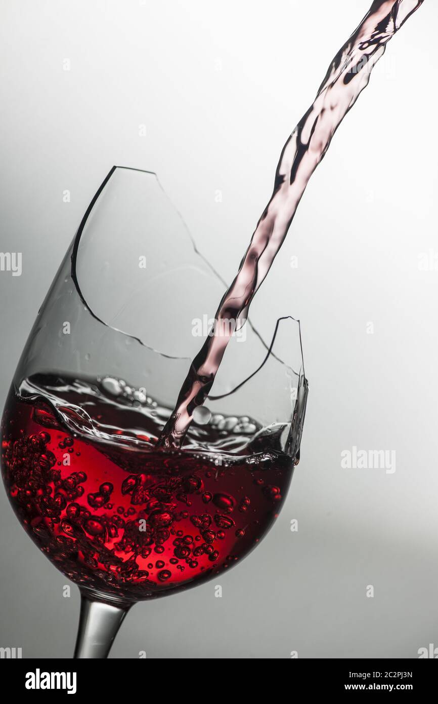Red wine pourin in a broken wine glass Stock Photo