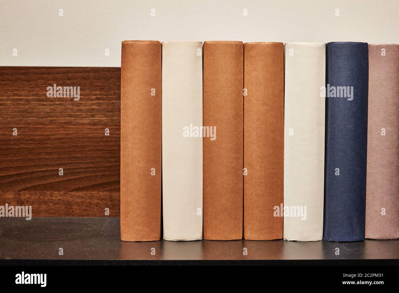 Wooden book shelf with series of books, no titles shown, blank sides Stock Photo