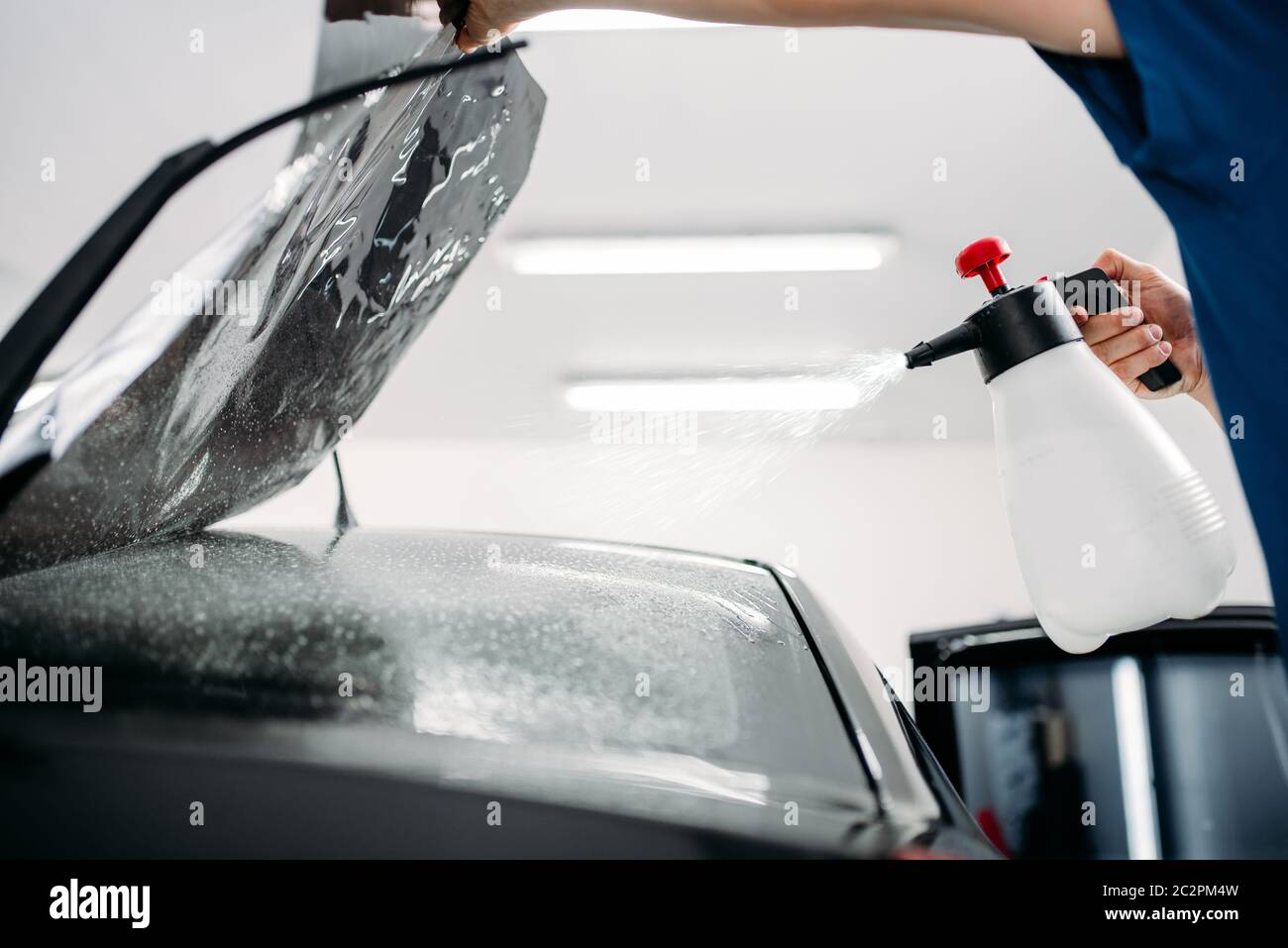Male hand with spray, car window tint installation process, installing procedure, tinting film