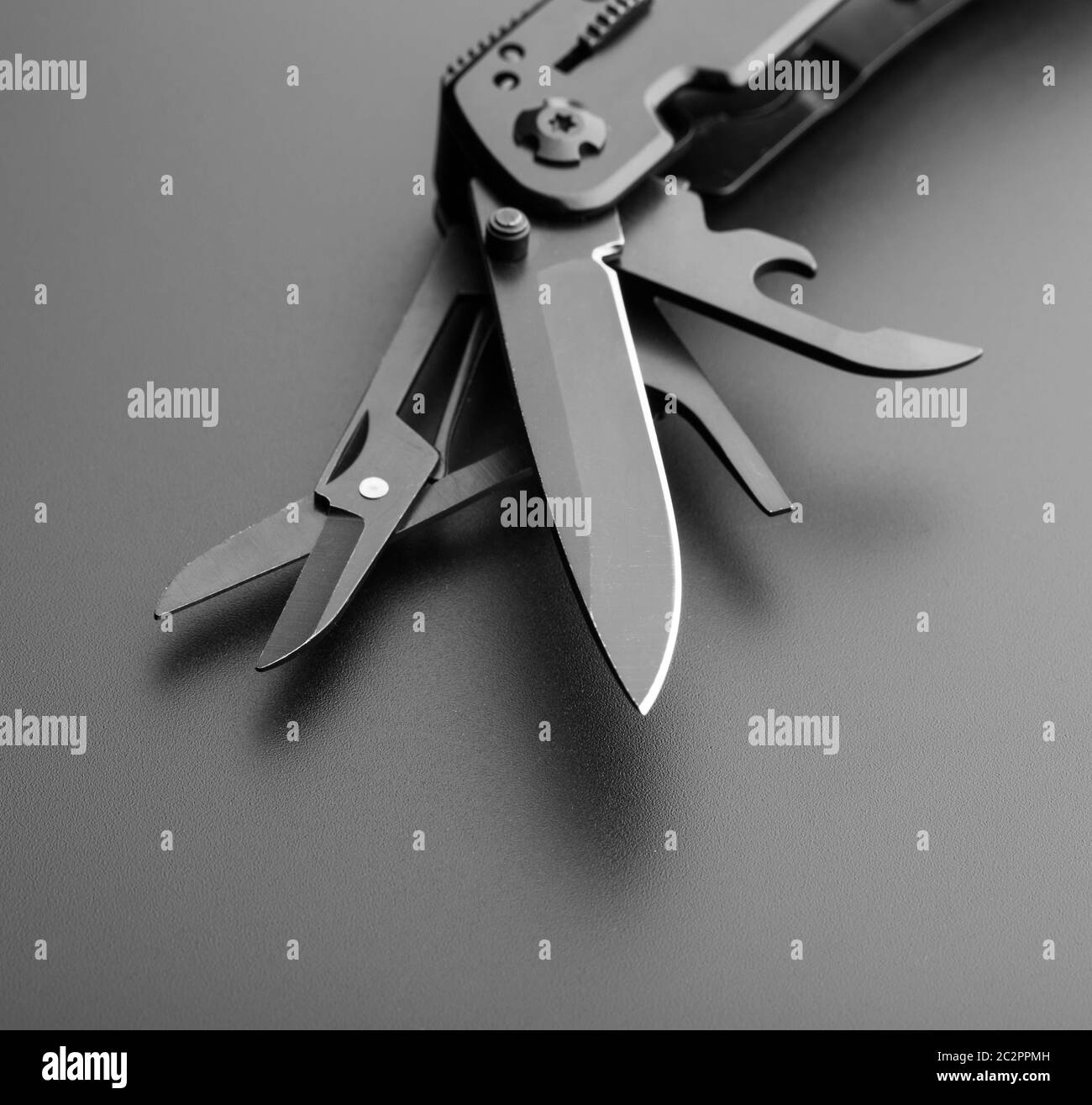 Black opened multitool knife on grey Stock Photo