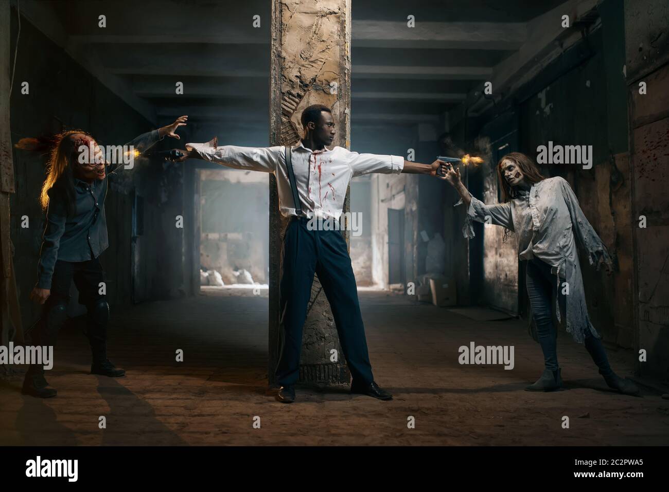 Man with two guns shoots zombies, deadly chase in abandoned factory. Horror in city, creepy crawlies attack, doomsday apocalypse, bloody evil monsters Stock Photo