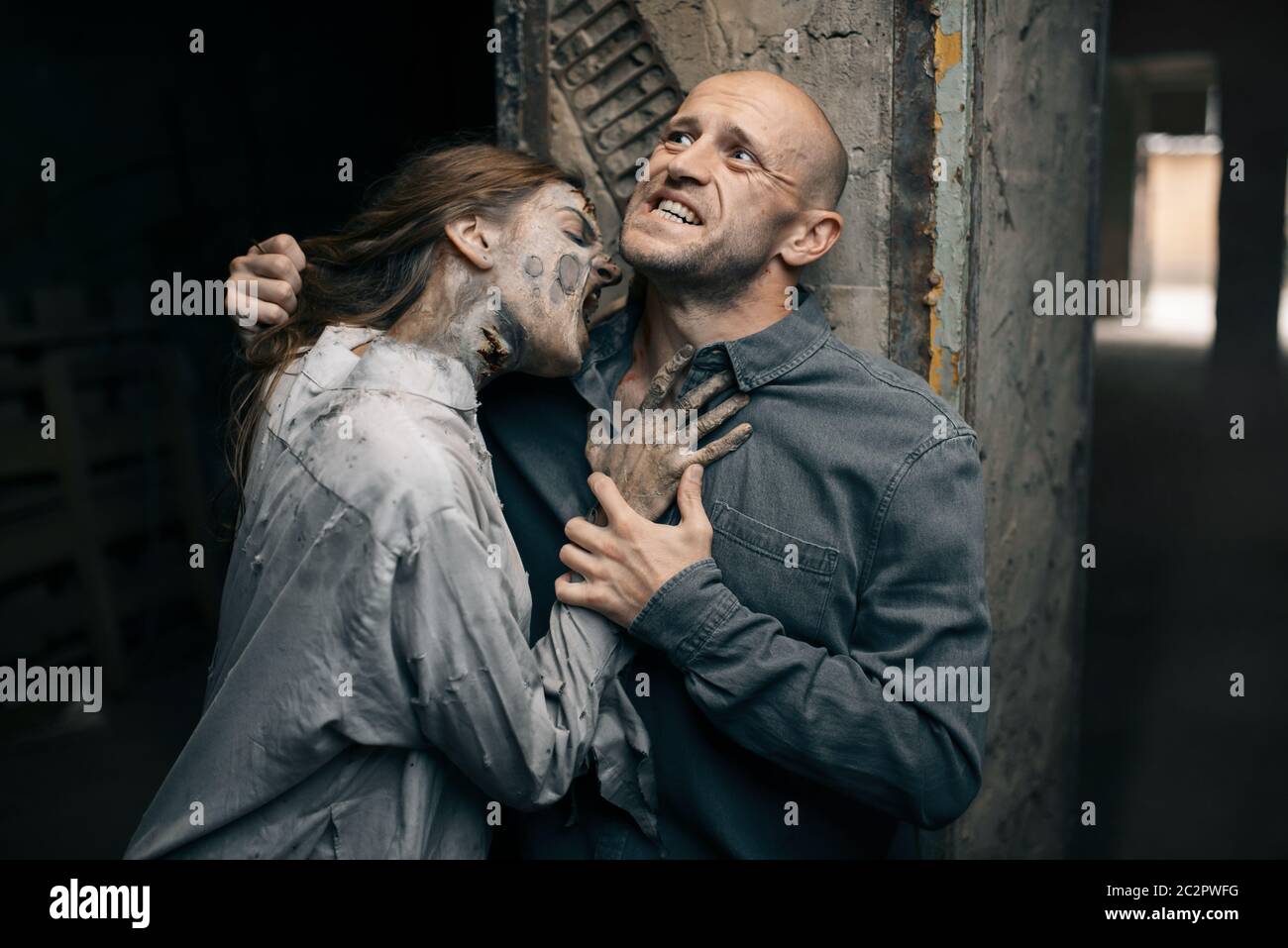 Female zombie bites a man in the neck, death trap, deadly chase. Horror in city, creepy crawlies attack, doomsday apocalypse Stock Photo