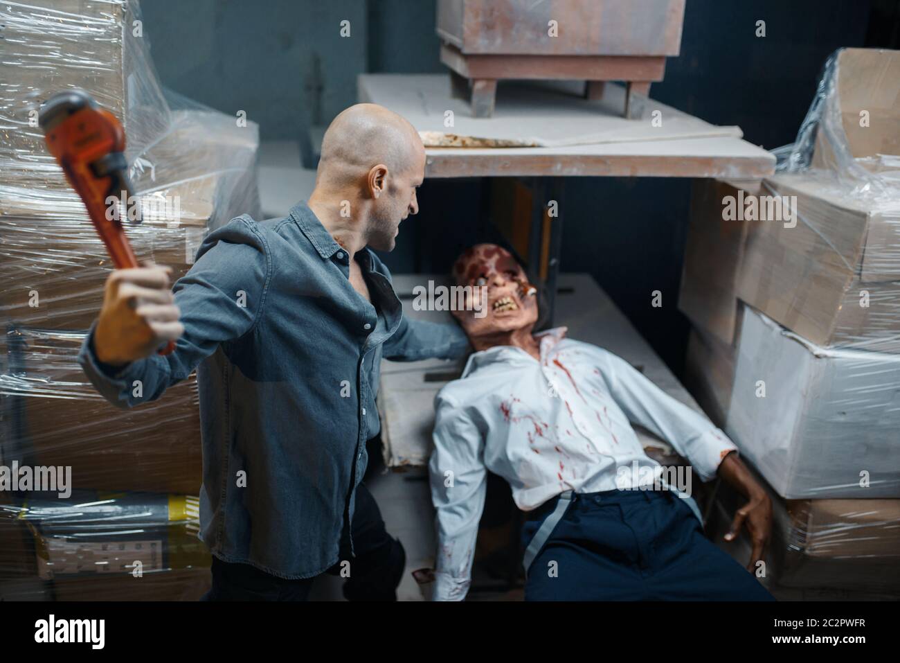 Man with pipe wrench kills zombie, deadly chase. Horror in city, creepy crawlies attack, doomsday apocalypse, bloody monster Stock Photo
