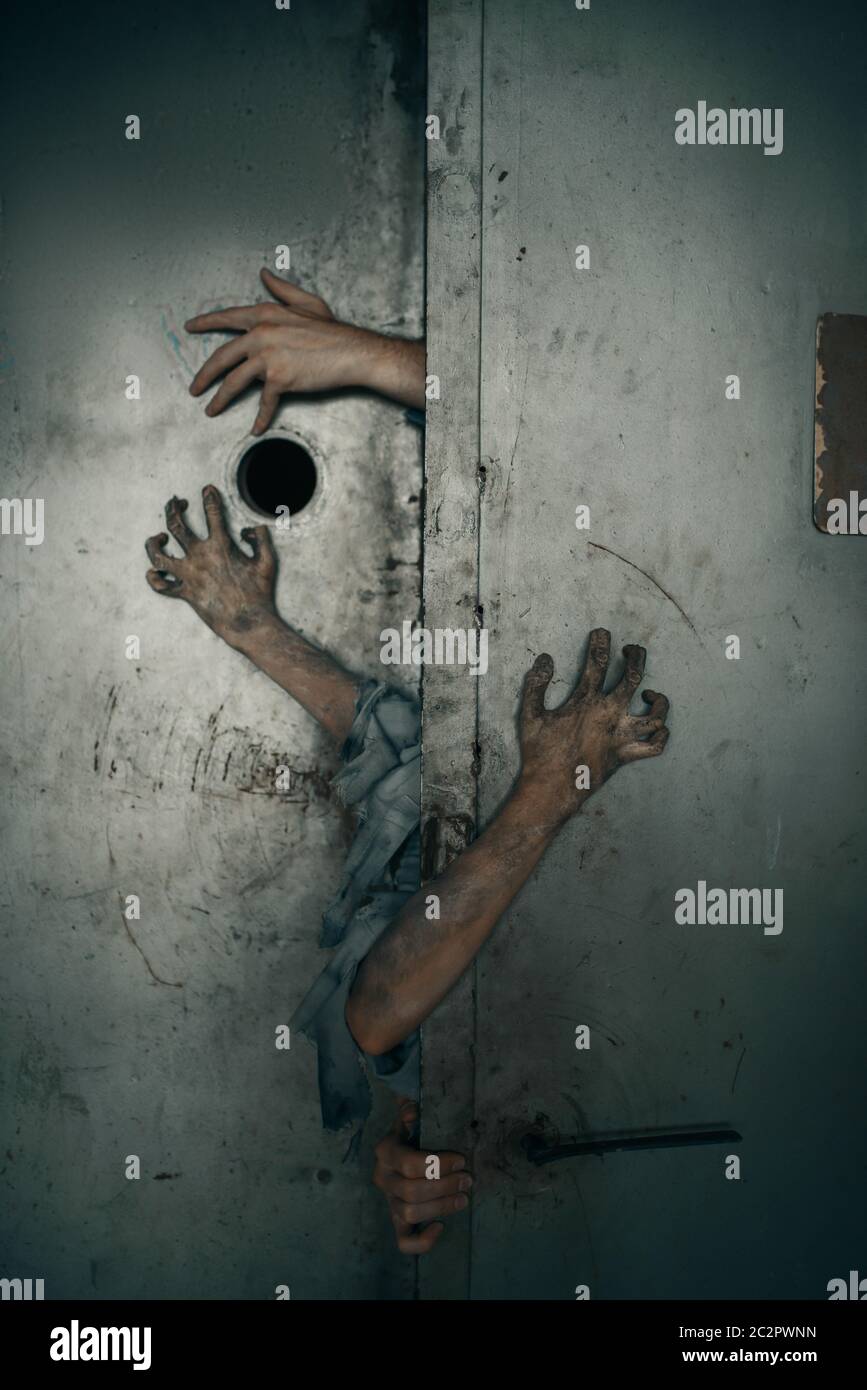 Zombie hands sticking out of the elevator door, deadly chase. Horror in city, creepy crawlies attack, doomsday apocalypse, bloody monsters Stock Photo