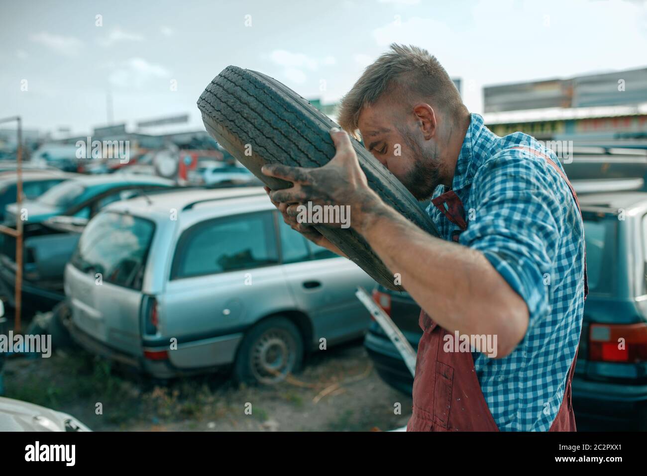 male-repairman-pumps-the-tire-with-his-mouth-on-car-scrapyard-auto-scrap-vehicle-junk-automobile-garbage-abandoned-damaged-and-crushed-transport-2C2PXX1.jpg