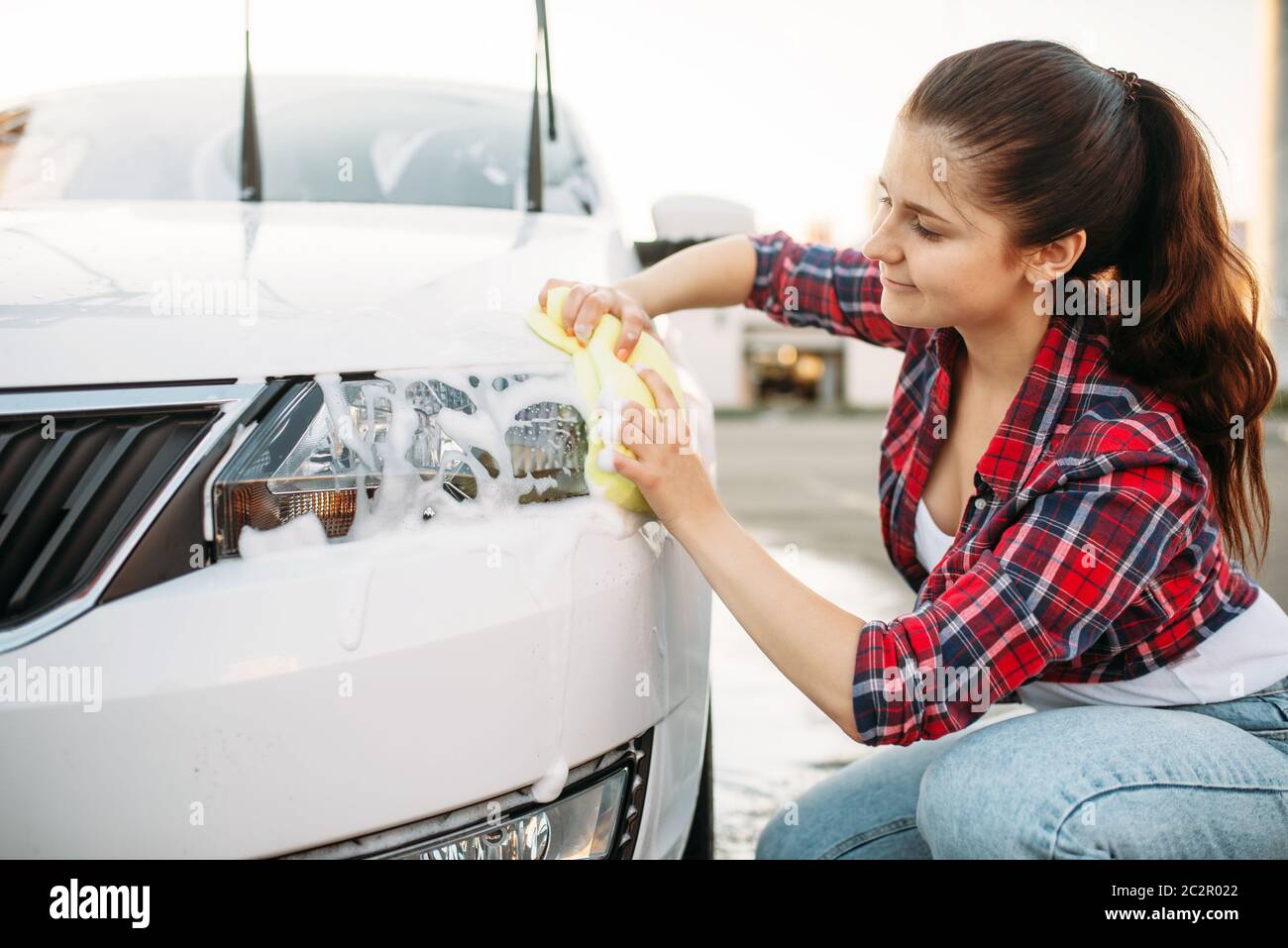 Cute woman with sponge scrubbing vehicle wheel with foam, car wash. Lady on  self-service automobile washing. Outdoor carwash at summer day Stock Photo  - Alamy