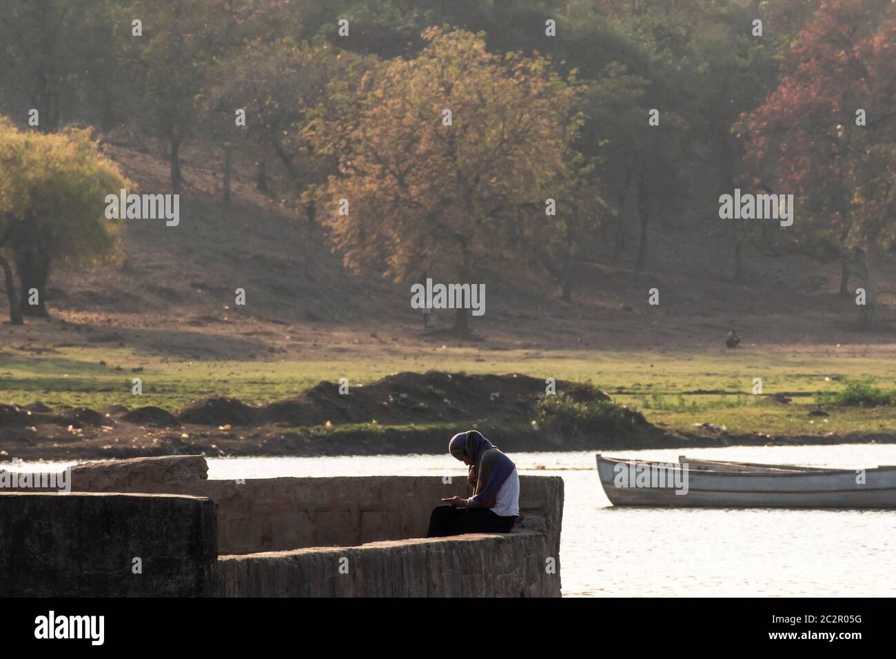 Nagpur, Maharahstra, India - March 2019: A young Indian girl wearing a veil sitting alone by beautiful setting of the Futala lake in the city. Stock Photo