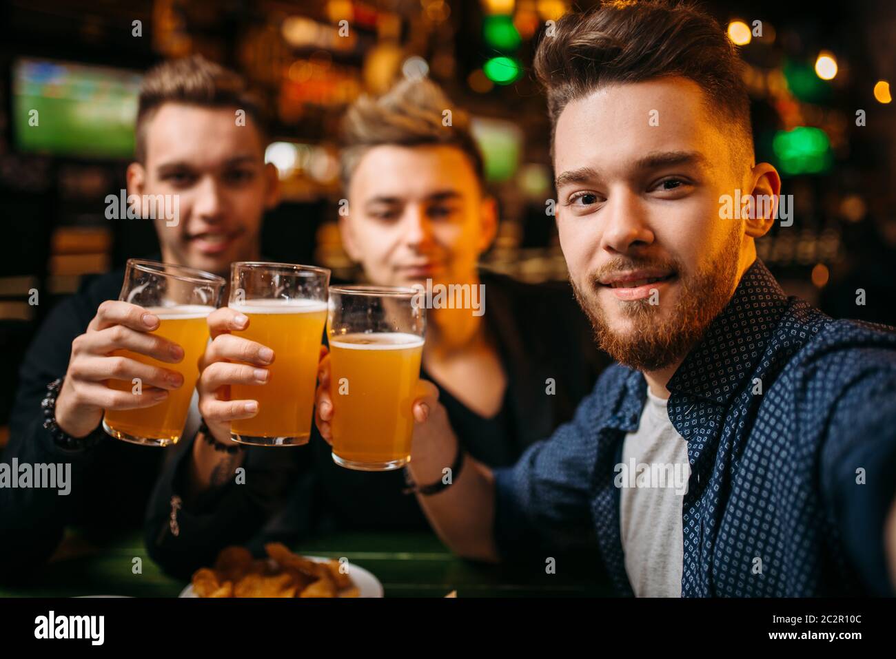 Three men raised their glasses with beer for game victory in a sport ...