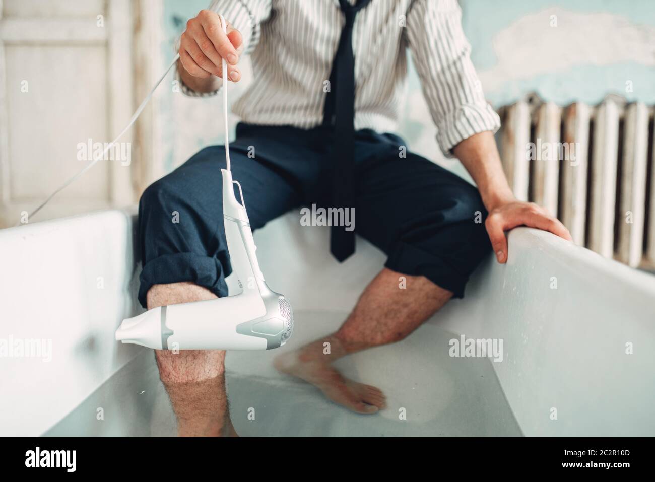 Businessman bankrupt with hairdryer in bathtub, suicide man concept