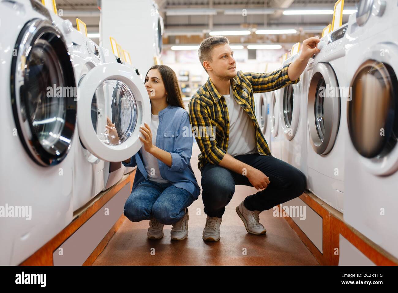 Family couple choosing washing machine in electronics store. Man