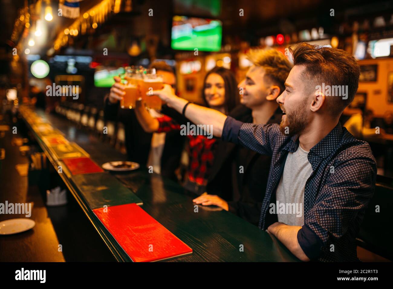 Happy football fans raised their glasses with beer at the bar counter