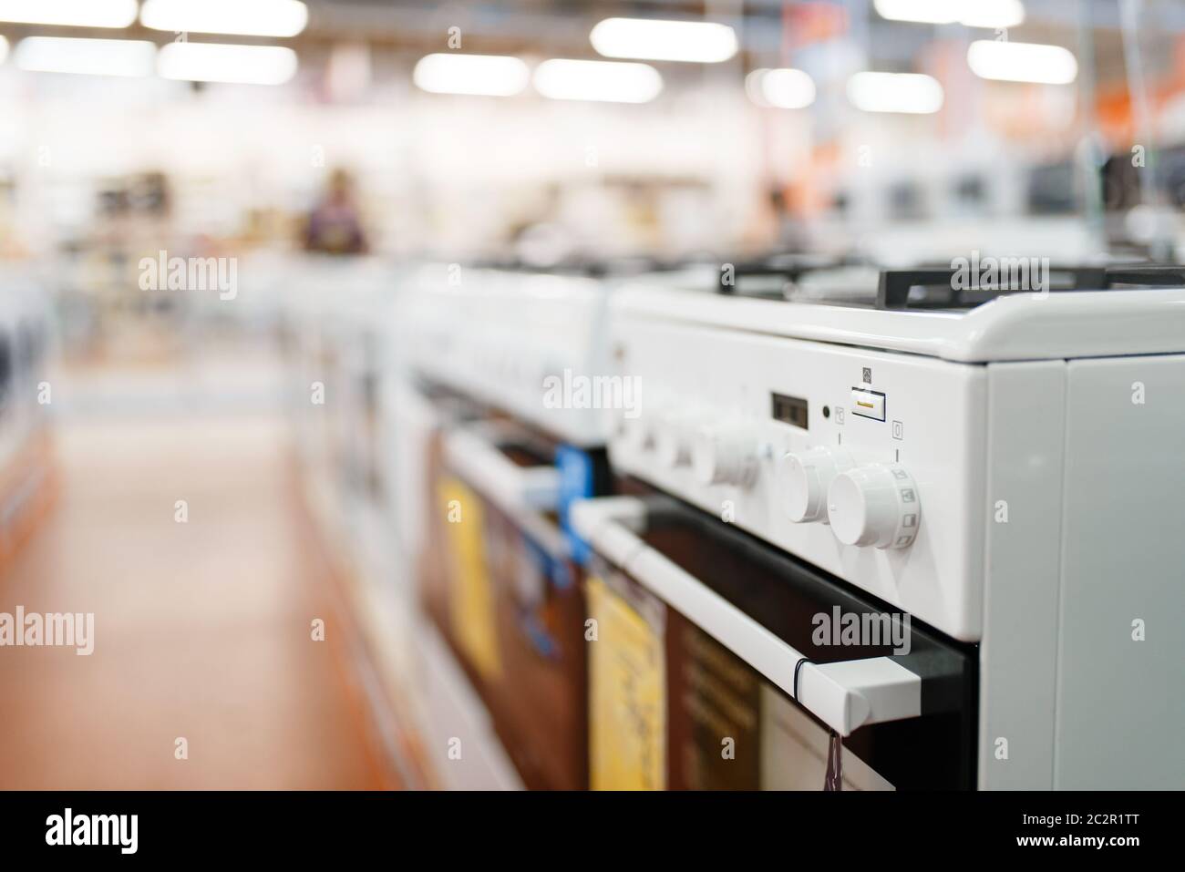 Row of new gas stoves in electronics store, nobody. Electric home appliances sale in supermarket Stock Photo