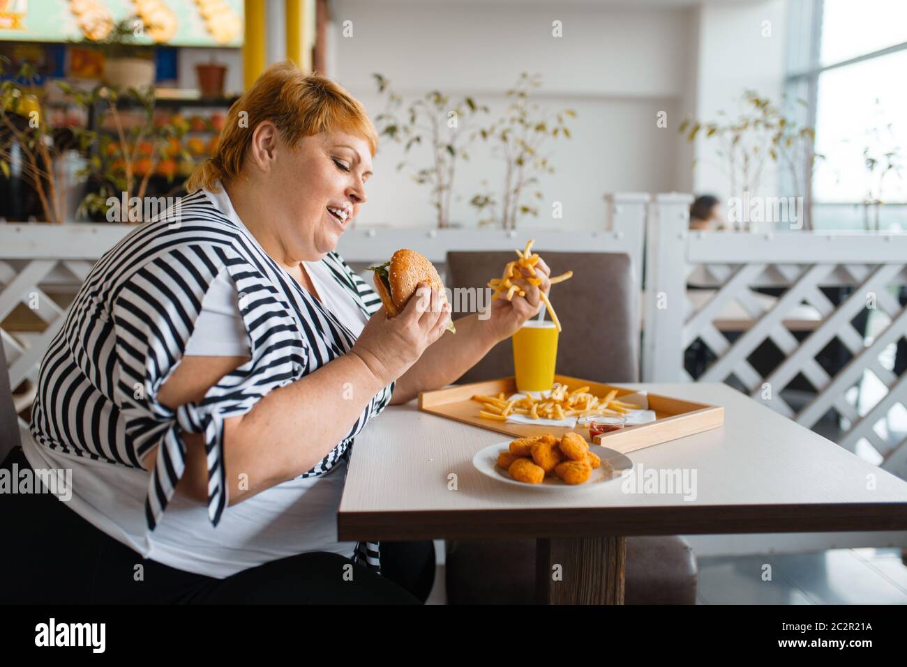 Fat woman eating high calorie food in fastfood restaurant. Overweight  female person at the table with junk dinner, obesity problem Stock Photo -  Alamy
