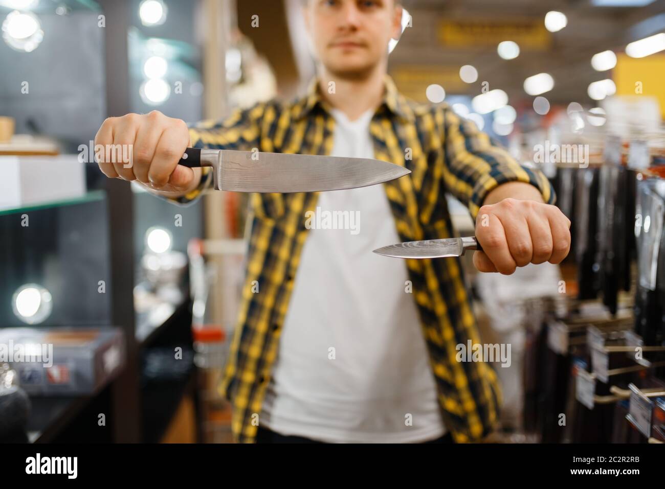 https://c8.alamy.com/comp/2C2R2RB/young-man-holds-kitchen-knives-in-houseware-store-male-person-buying-home-goods-in-market-guy-in-kitchenware-supply-shop-2C2R2RB.jpg