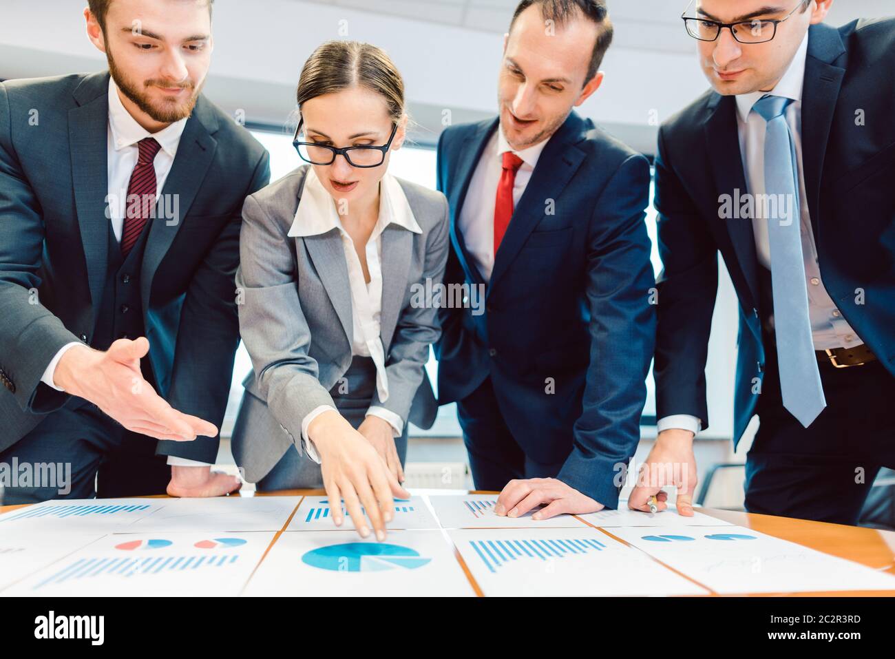 Team analyzing financial data in charts on a table discussing their ...