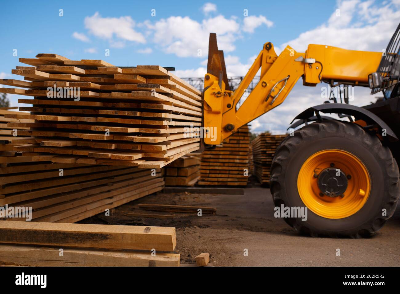 Forklift loads the boards in the lumber yard outdoor. Autoloader works
