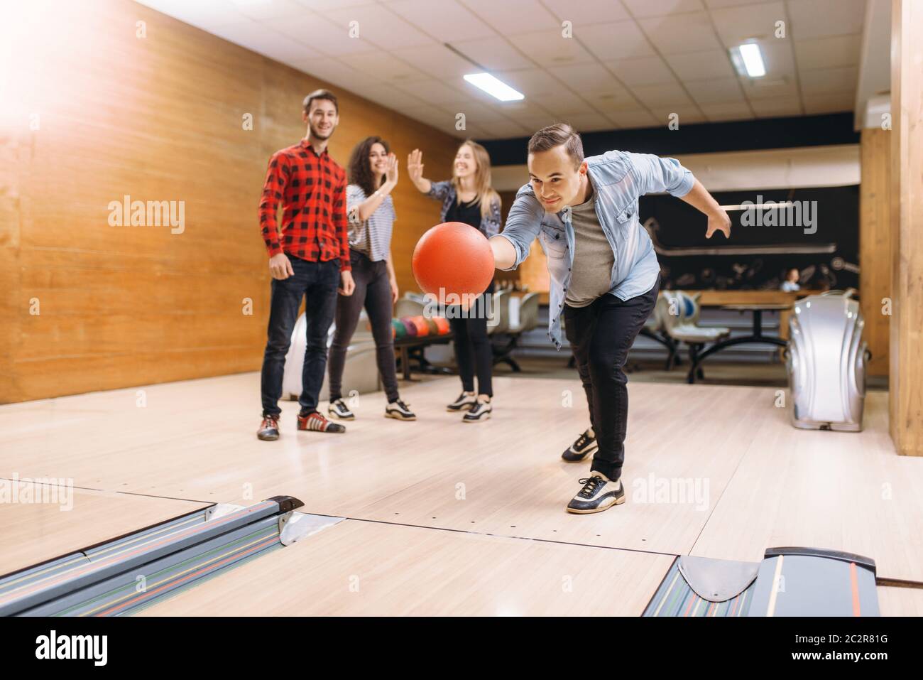 Male bowler throws ball on lane. Bowling alley teams playing the game in club, active leisure