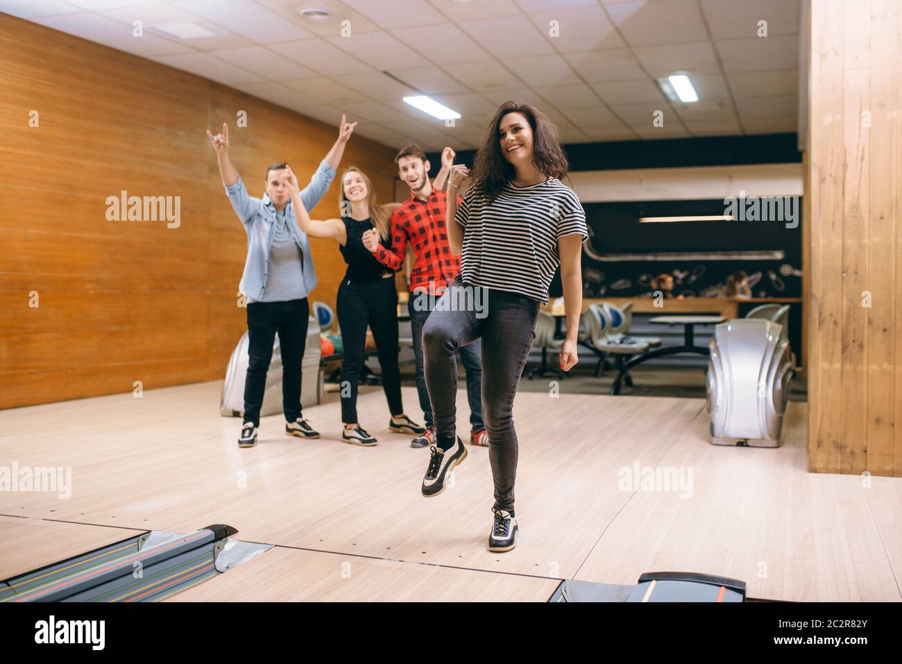 Female bowler throws ball on lane, strike shot. Bowling alley teams playing the game in club, active leisure Stock Photo