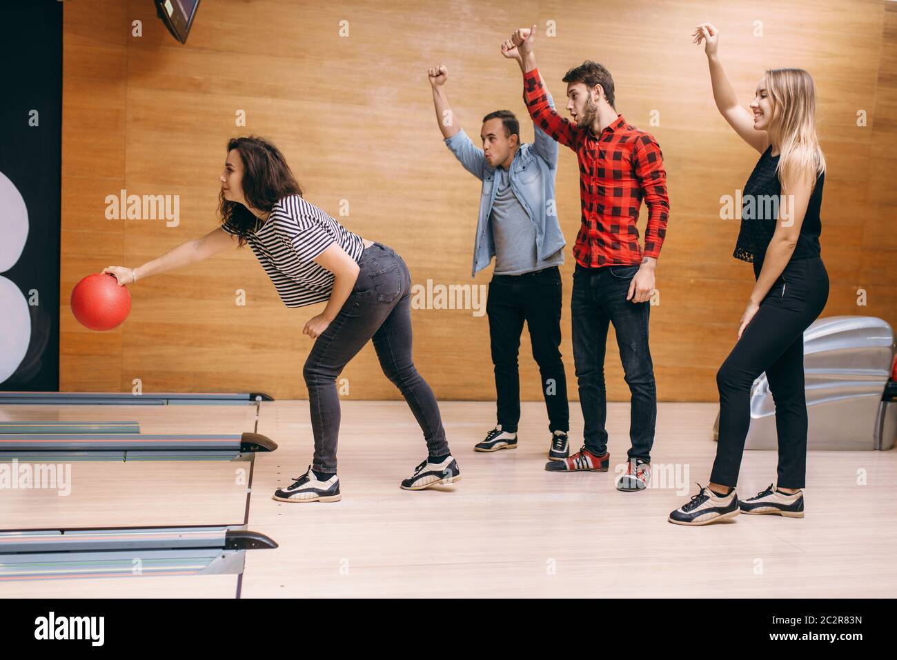 Female bowler on lane, ball throwing in action, strike shot preparation. Bowling alley teams playing the game in club, active leisure Stock Photo