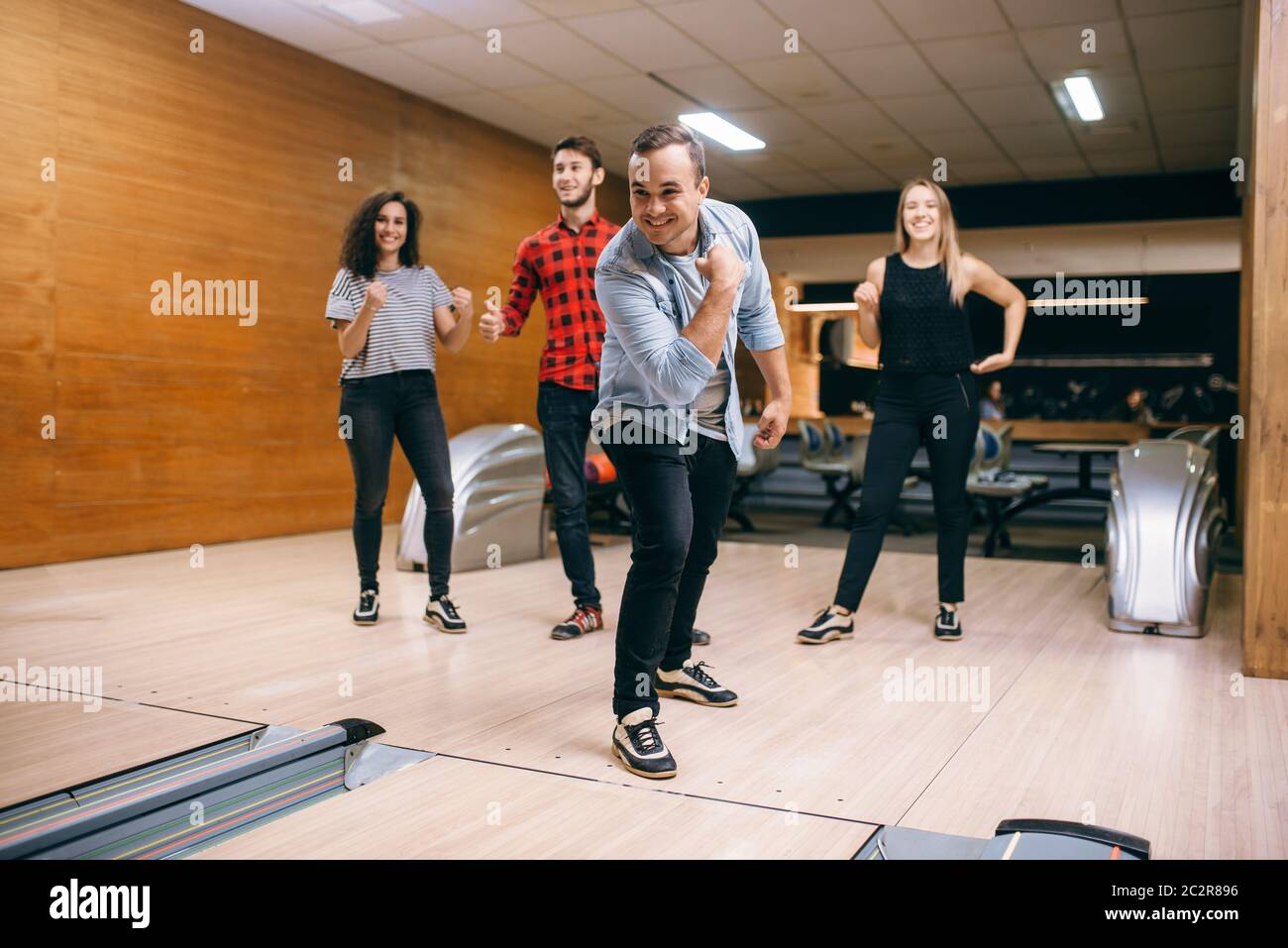 Male bowler throws ball on lane, strike shot. Bowling alley teams playing the game in club, active leisure Stock Photo