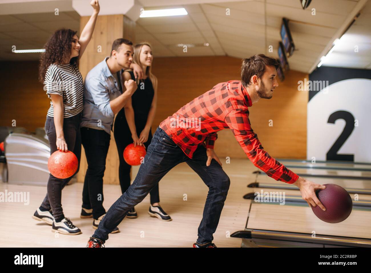 Male bowler throws ball on lane, front view, throwing in action. Bowling alley teams playing the game in club, active leisure Stock Photo
