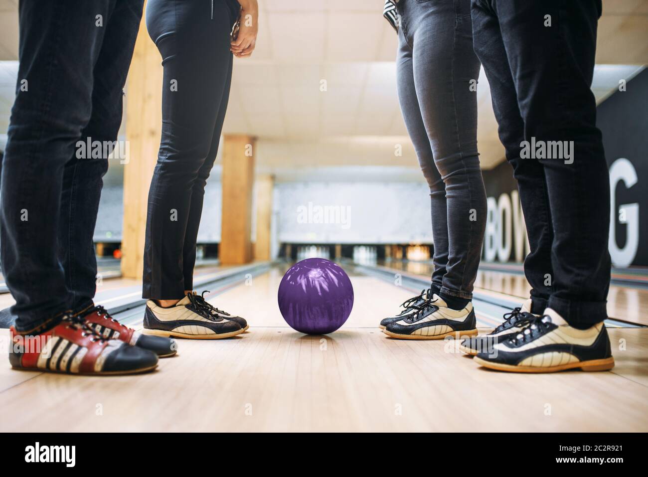 Bowling alley team, feet of the players in house shoes and ball on lane. Friends playing the game in club, active leisure Stock Photo