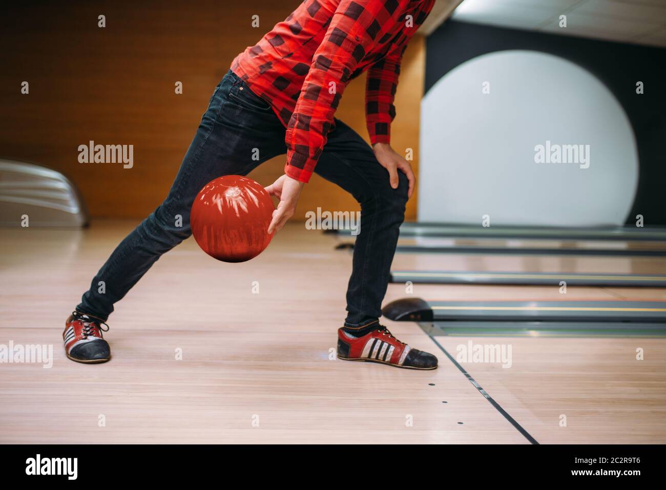 Male bowler makes throw, closeup view on hand with ball. Bowling alley player, throwing in action, classical tenpin game in club Stock Photo