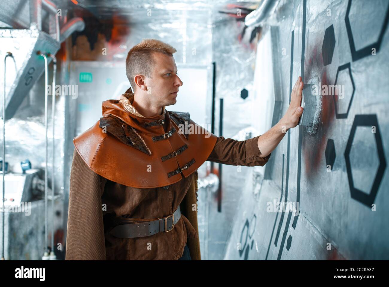 Space scientist holds wires at the control panel in spacecraft with foil walls. Fantasy spaceship for interstellar travel, future science and technolo Stock Photo